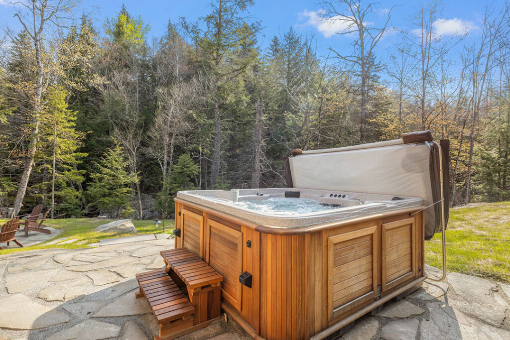 How tub in the woods surrounded by pine trees and others in a setting that is approaching autumn